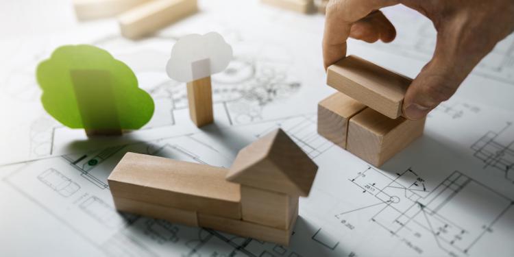 Picture of wooden block homes and a paper tree placed on a schematic of a building.