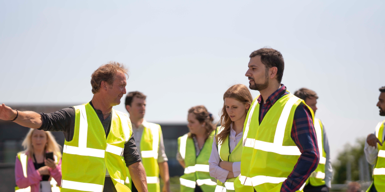 on the roof of the Royal Northern College of Music standing next to roof top solar panels., people walking in high visibility jackets together