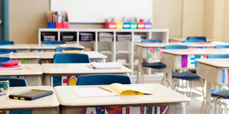 Classroom without children at school's out. The desks are in rows and you can read the names of the children on the front of the desks drawn in multicolour. 