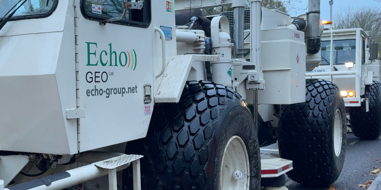 A large white truck with a green logo on its door 