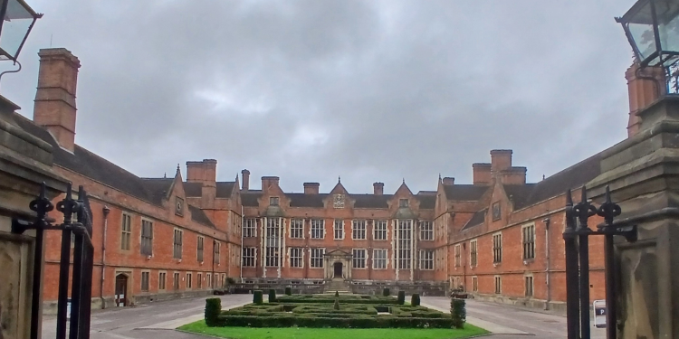 York University's grand, red brick building, Heslington tall, viewed from the entrance gates with a mini maze in its front courtyard.