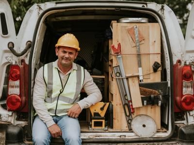 Man sitting in he back of his working van with tools