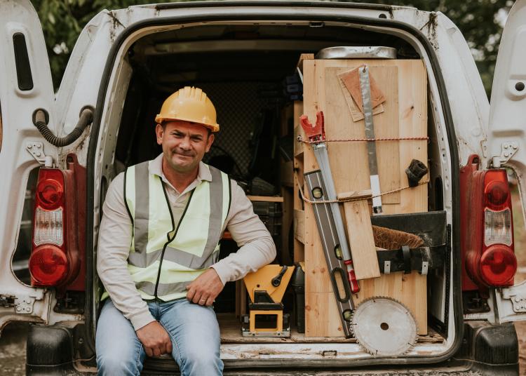 Man sitting in he back of his working van with tools