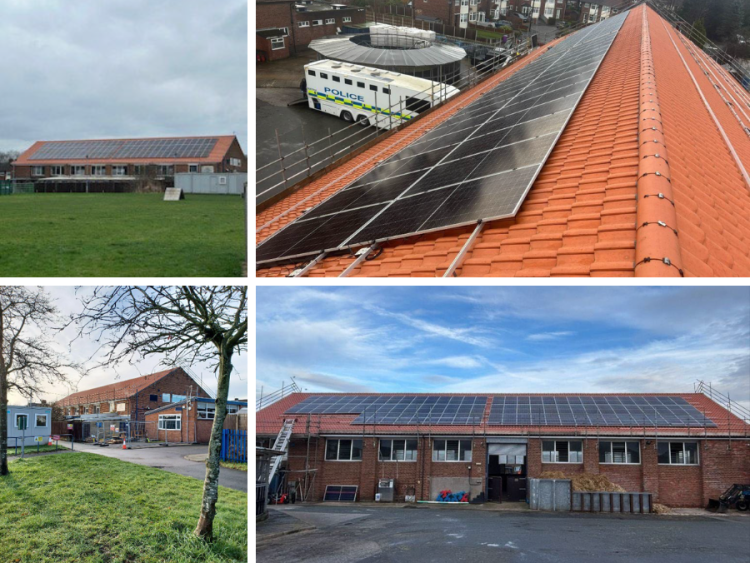 Black solar panels on top of a red brick building with a red roof.