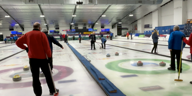 Two groups of curlers compete with stones spread around the targets